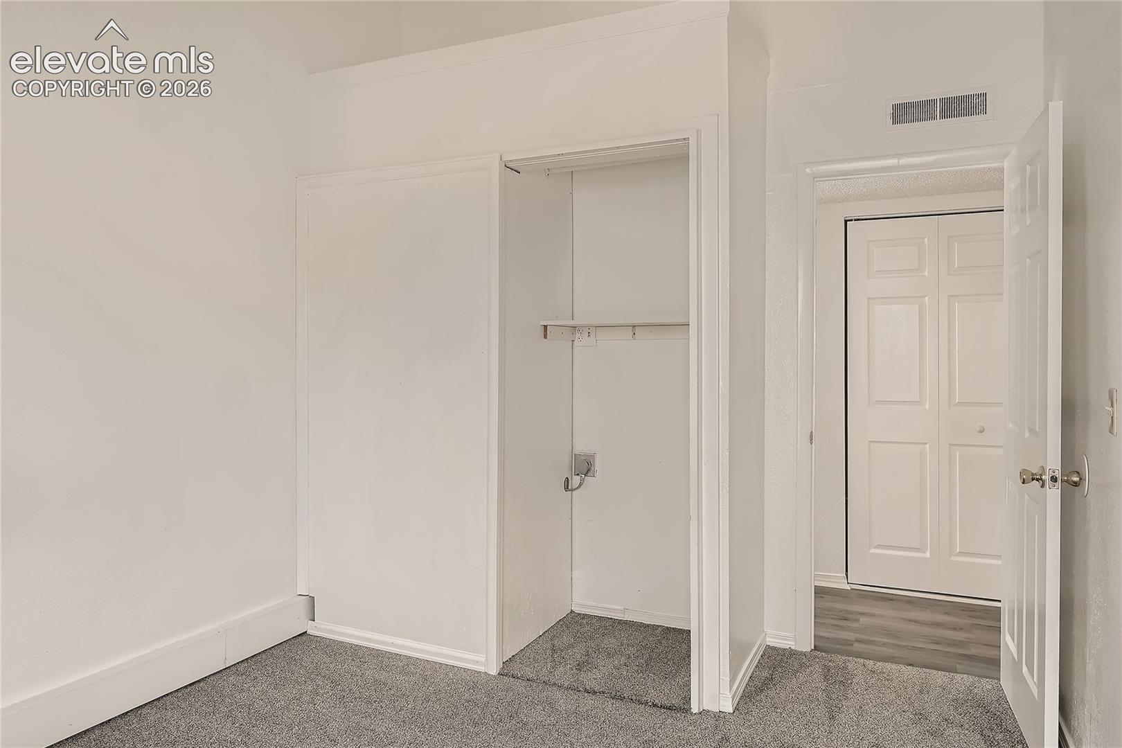 Wall-to-wall carpeting, closet featuring a built-in shelf and hanging rod, interior door with polished metal hardware, and bi-fold closet doors