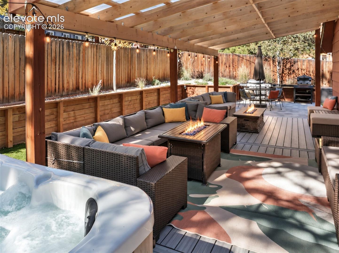 Covered wooden pergola, composite decking, built-in hot tub, and wood privacy fencing