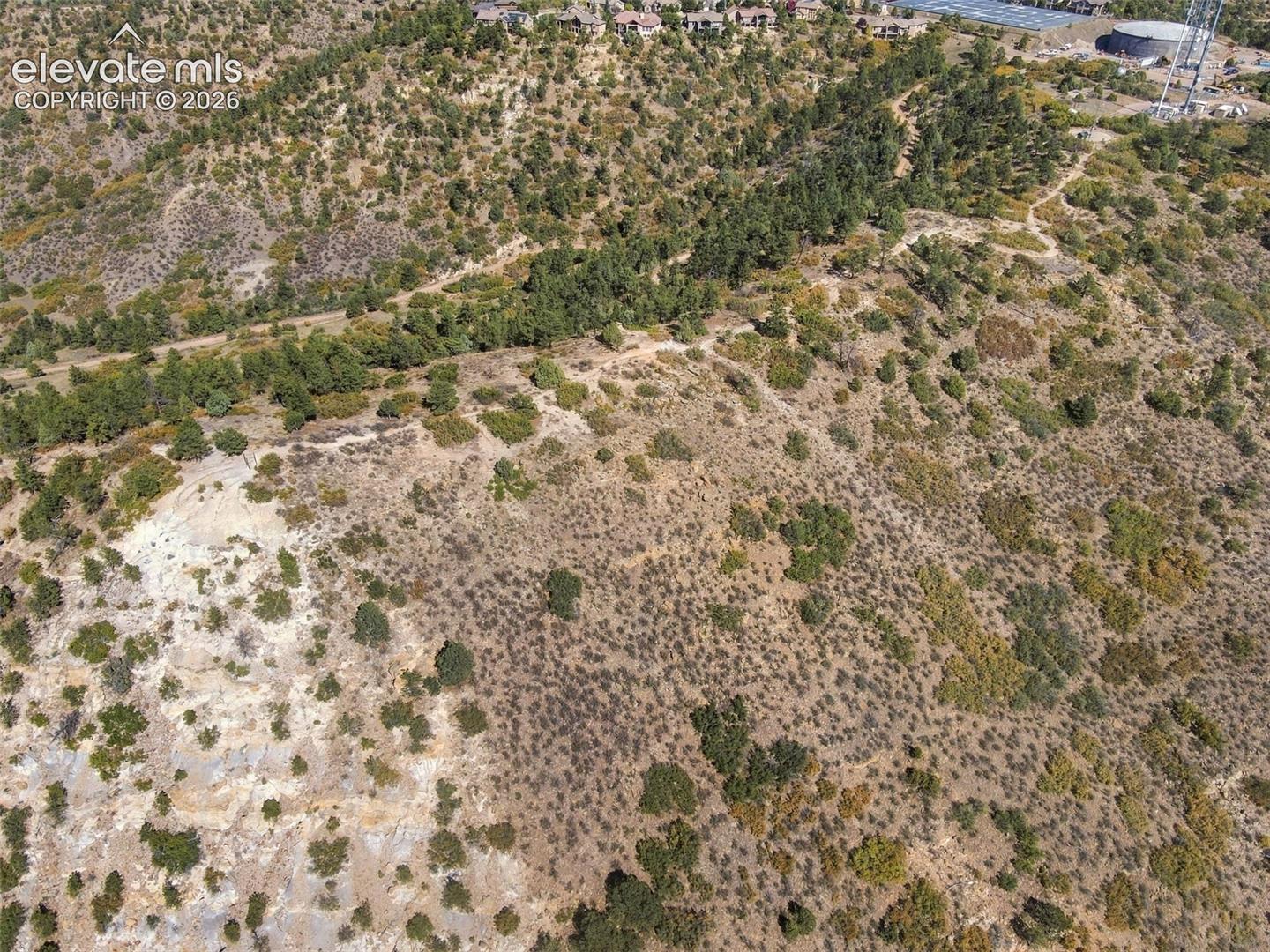 Elevated hillside parcel featuring native vegetation, exposed rock outcroppings, and coniferous trees