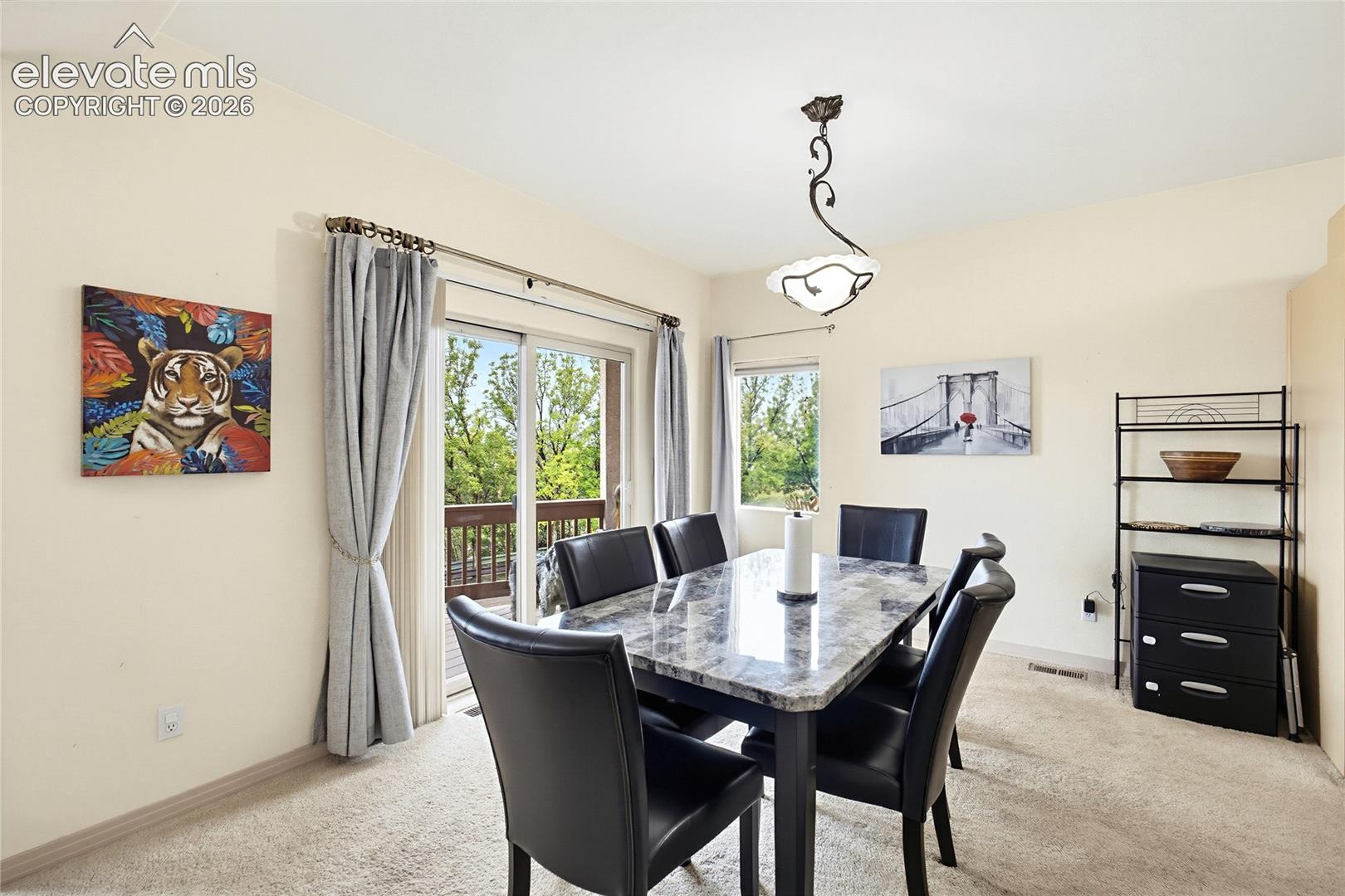 Dining area featuring carpet flooring, a sliding glass door to an outdoor deck, and an overhead decorative light fixture
