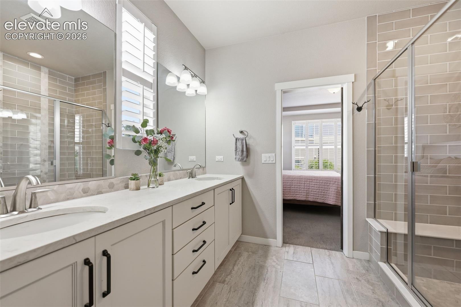 Double vanity with undermount sinks, white stone countertops, and black cabinet hardware.