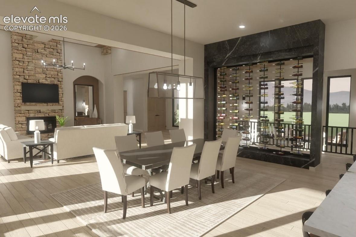 Open-concept living area featuring a stone fireplace, vaulted ceilings, and wood-finish flooring