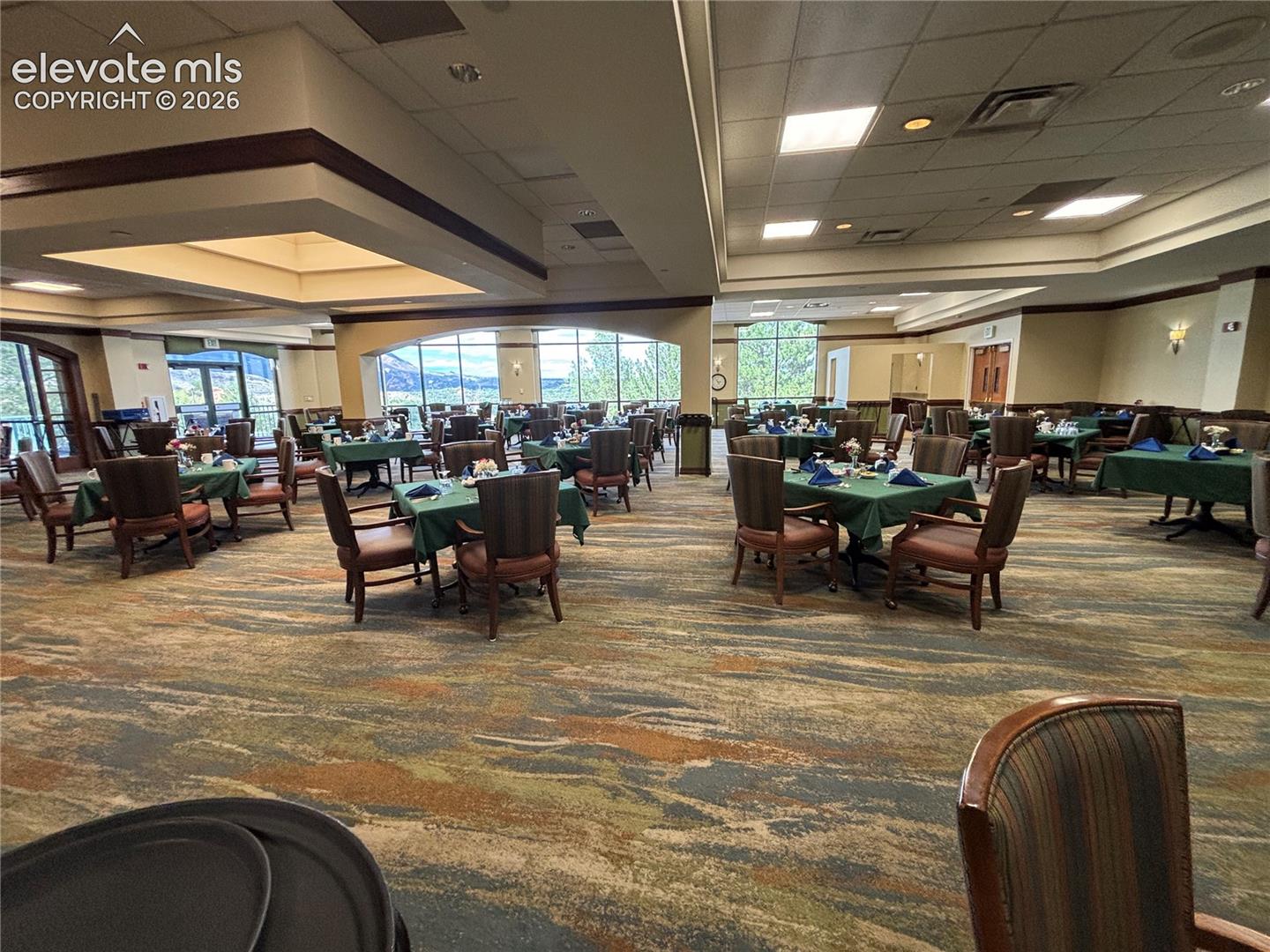 Expansive dining area featuring a patterned carpet, large windows, recessed lighting, and tray ceilings