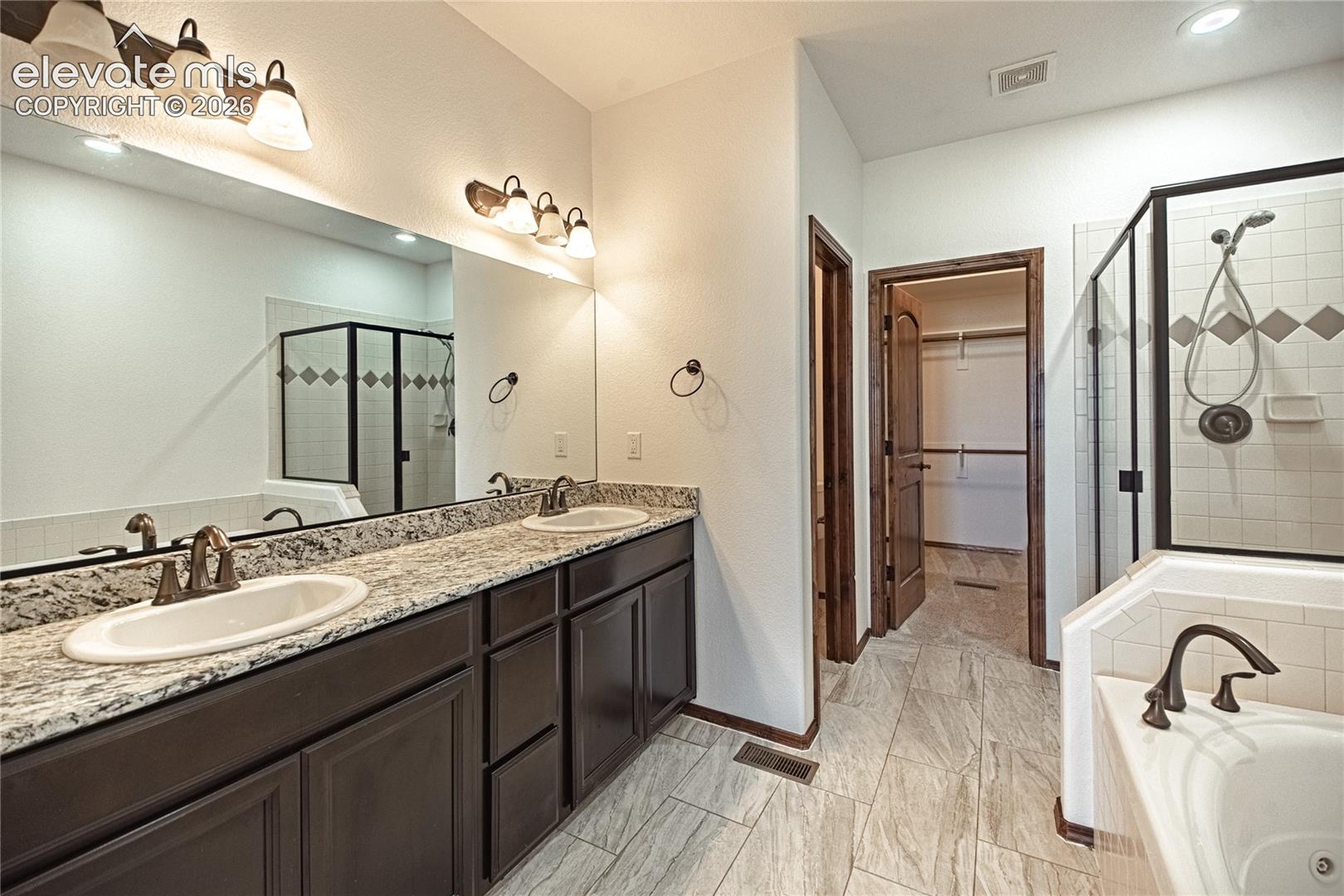 Double vanity with granite countertop, individual sinks, and bronze-finish fixtures
