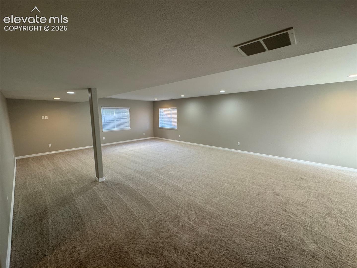 Open-concept interior featuring neutral wall tones, recessed lighting, wall-to-wall carpeting, and double-pane windows