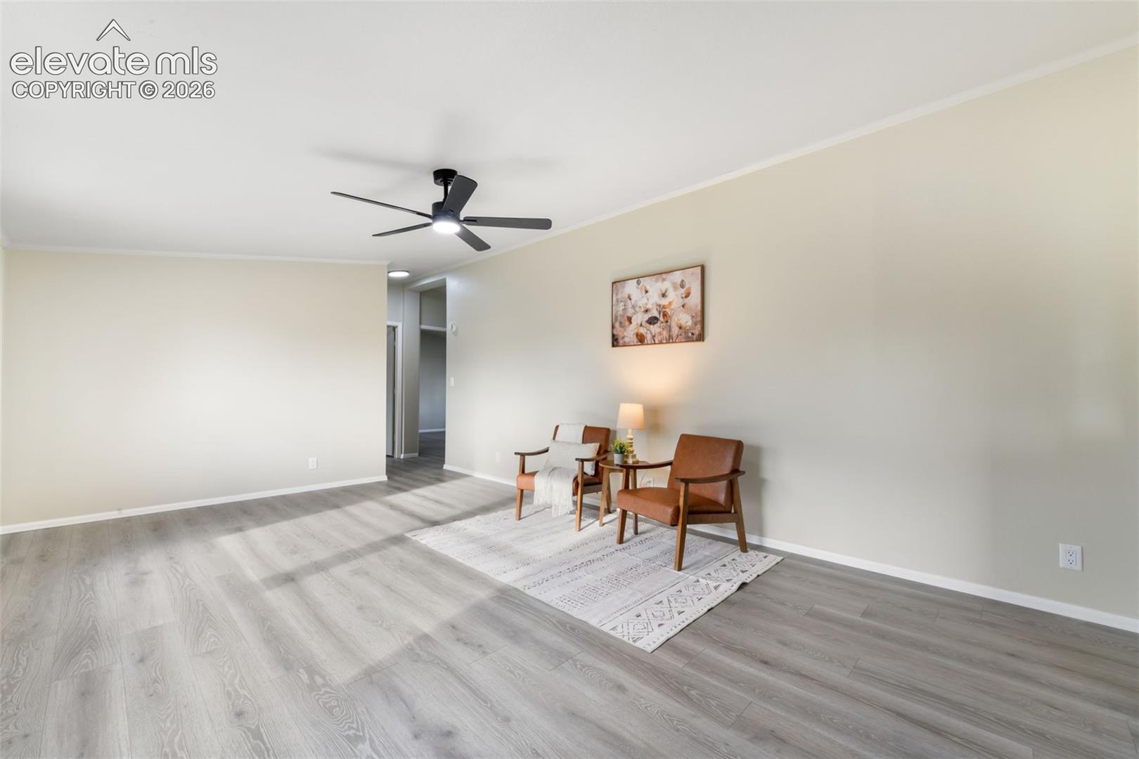 Spacious room with light neutral wall tones, wood-finish flooring, and a modern ceiling fan with lighting