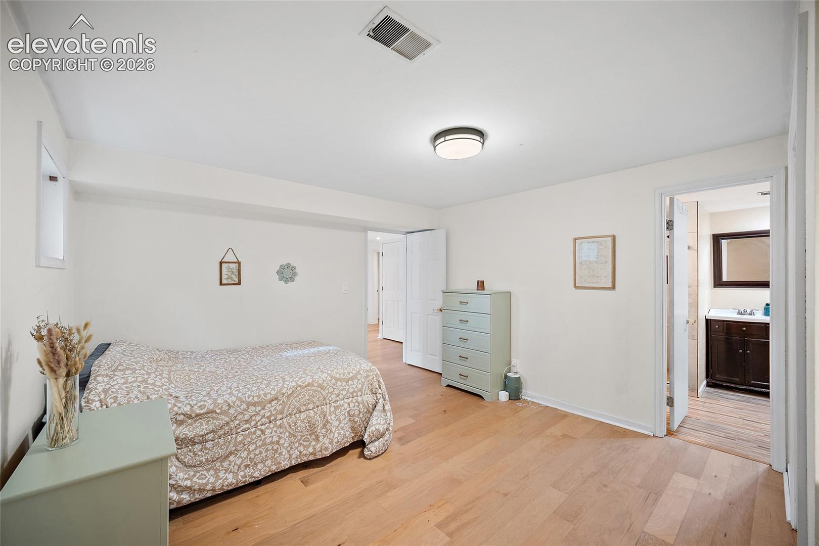Wood-finish flooring, neutral wall tones, interior door with hardware, and flush-mount ceiling light fixture