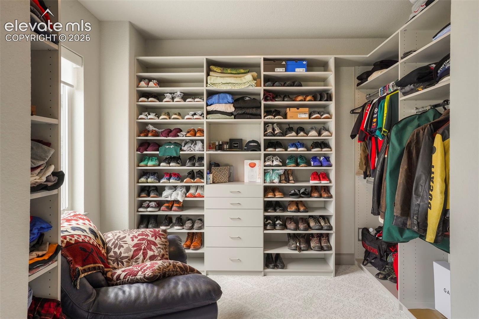 Custom closet system featuring extensive shelving, integrated drawer units, hanging space, and carpet flooring
