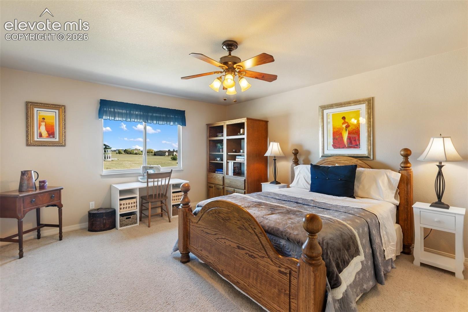 Neutral wall coloring, carpeted flooring, built-in wooden shelving unit, and a ceiling fan with integrated multi-bulb lighting fixture