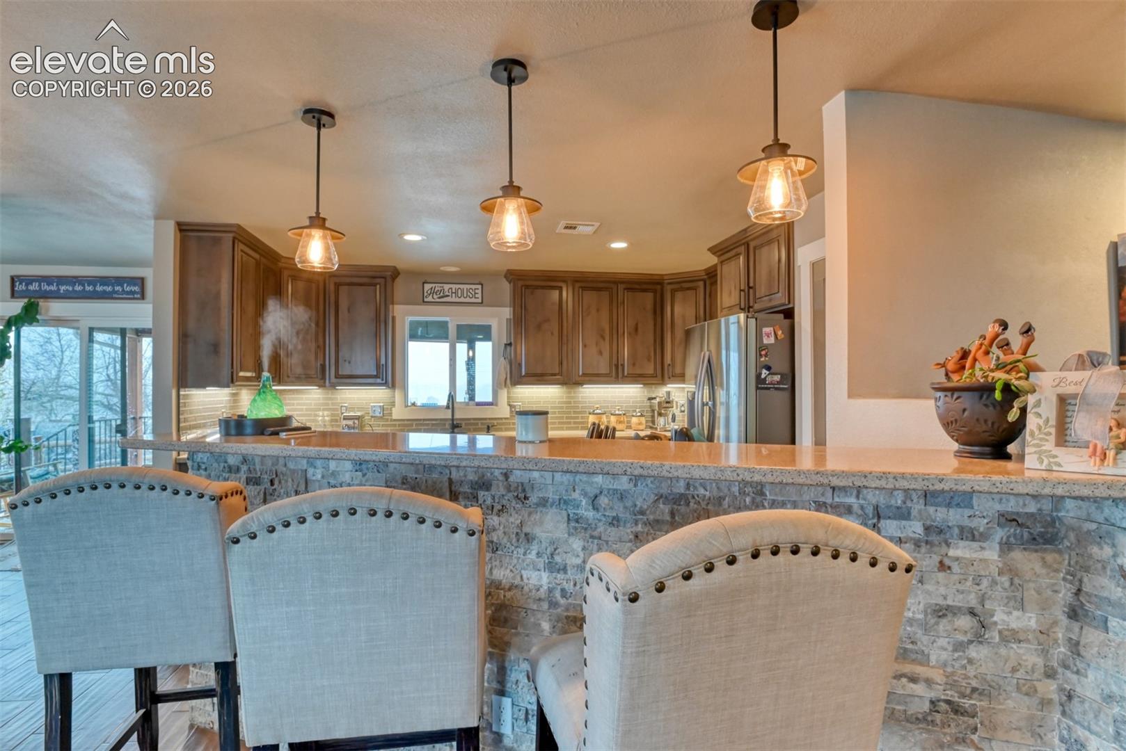 Kitchen featuring stainless steel fridge, tasteful backsplash, a breakfast bar area, and wood finish cabinetry