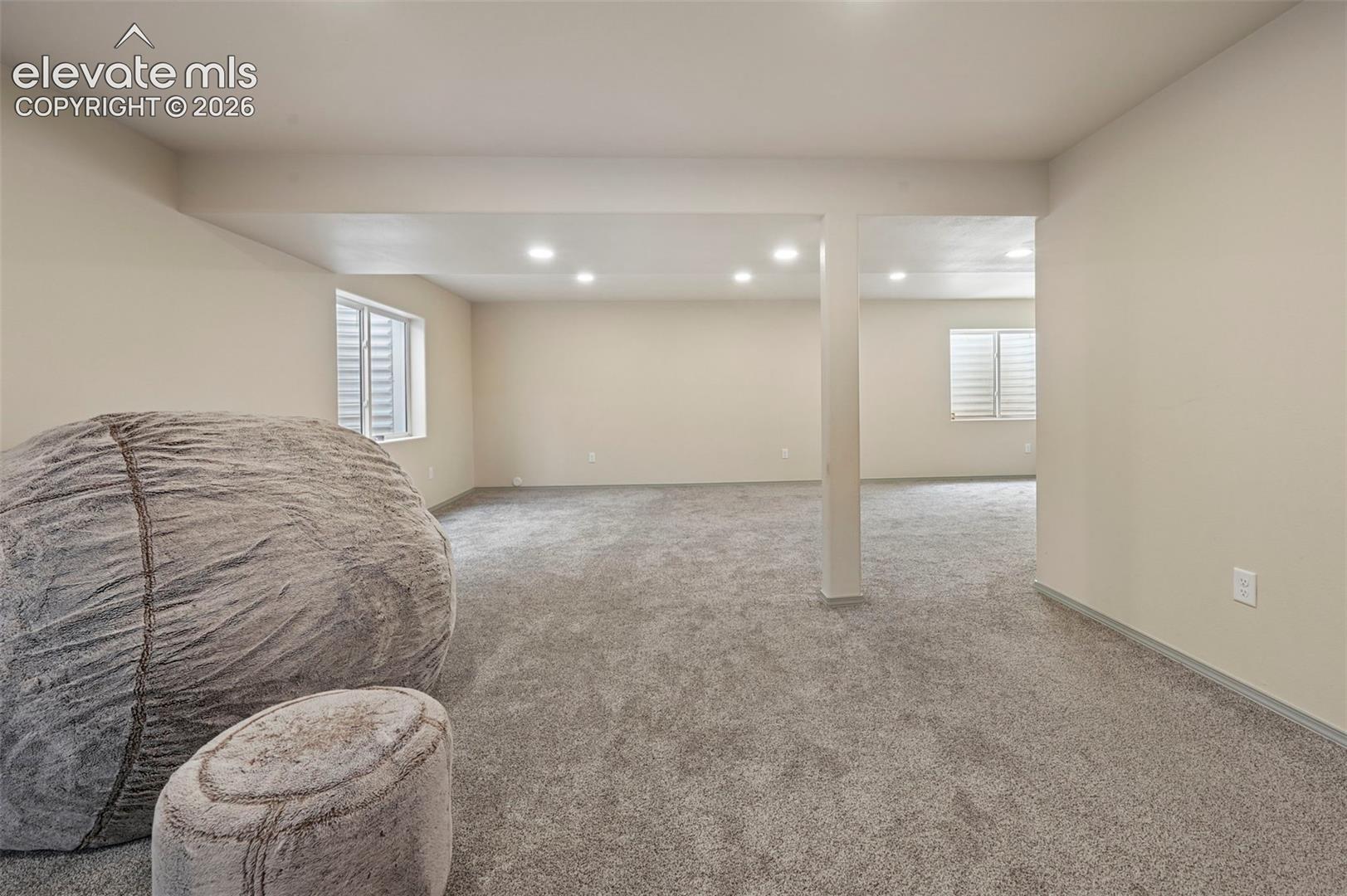 Spacious room featuring neutral paint, gray carpeting, recessed lighting, and white window shutters
