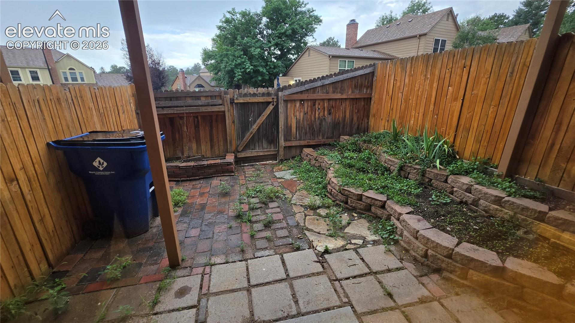 Paver and flagstone patio, wood fence, and tiered garden bed