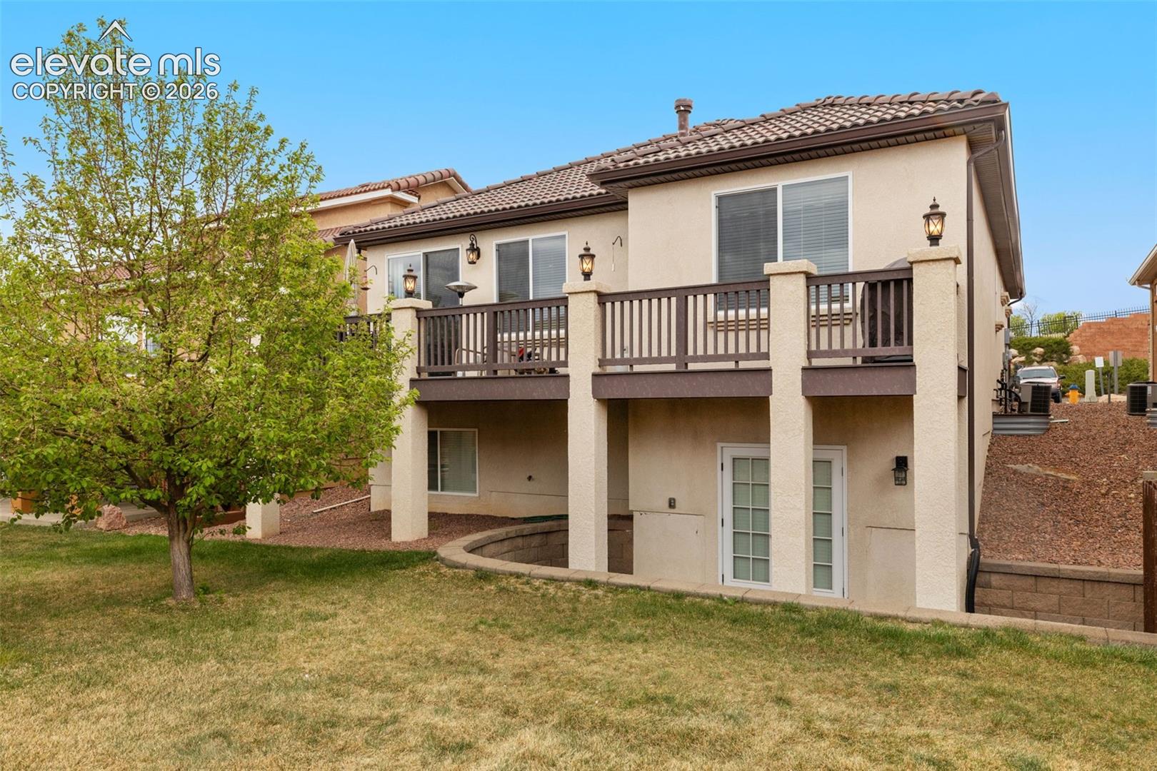 Stucco exterior with a tiled roof and French doors opening to lower patio.