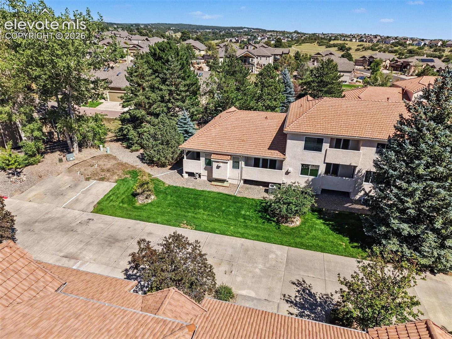 Stucco exterior residence featuring a tiled roof, multiple windows, and a concrete driveway