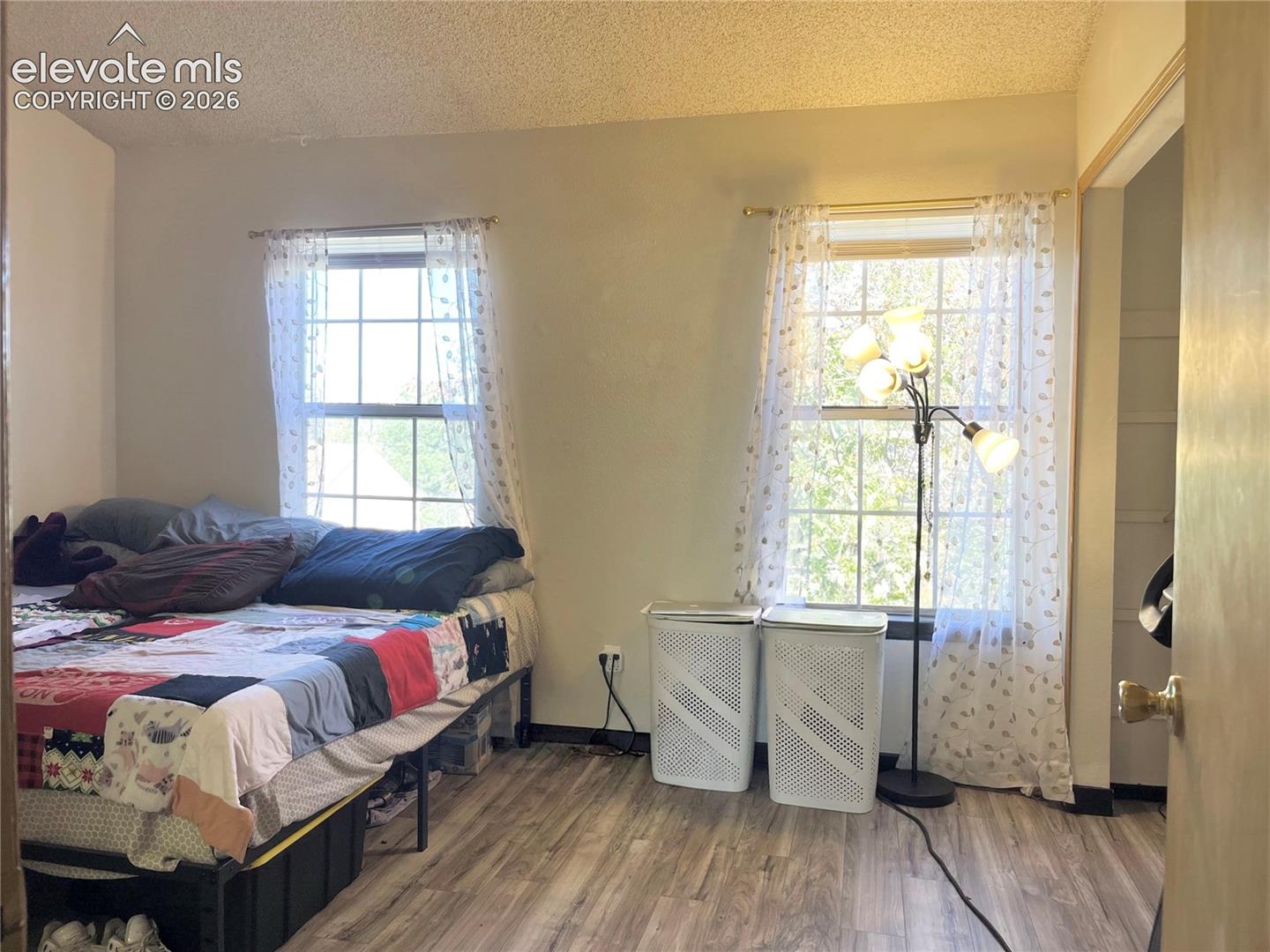 Room featuring wood-finish flooring, two multi-pane windows, and a textured ceiling