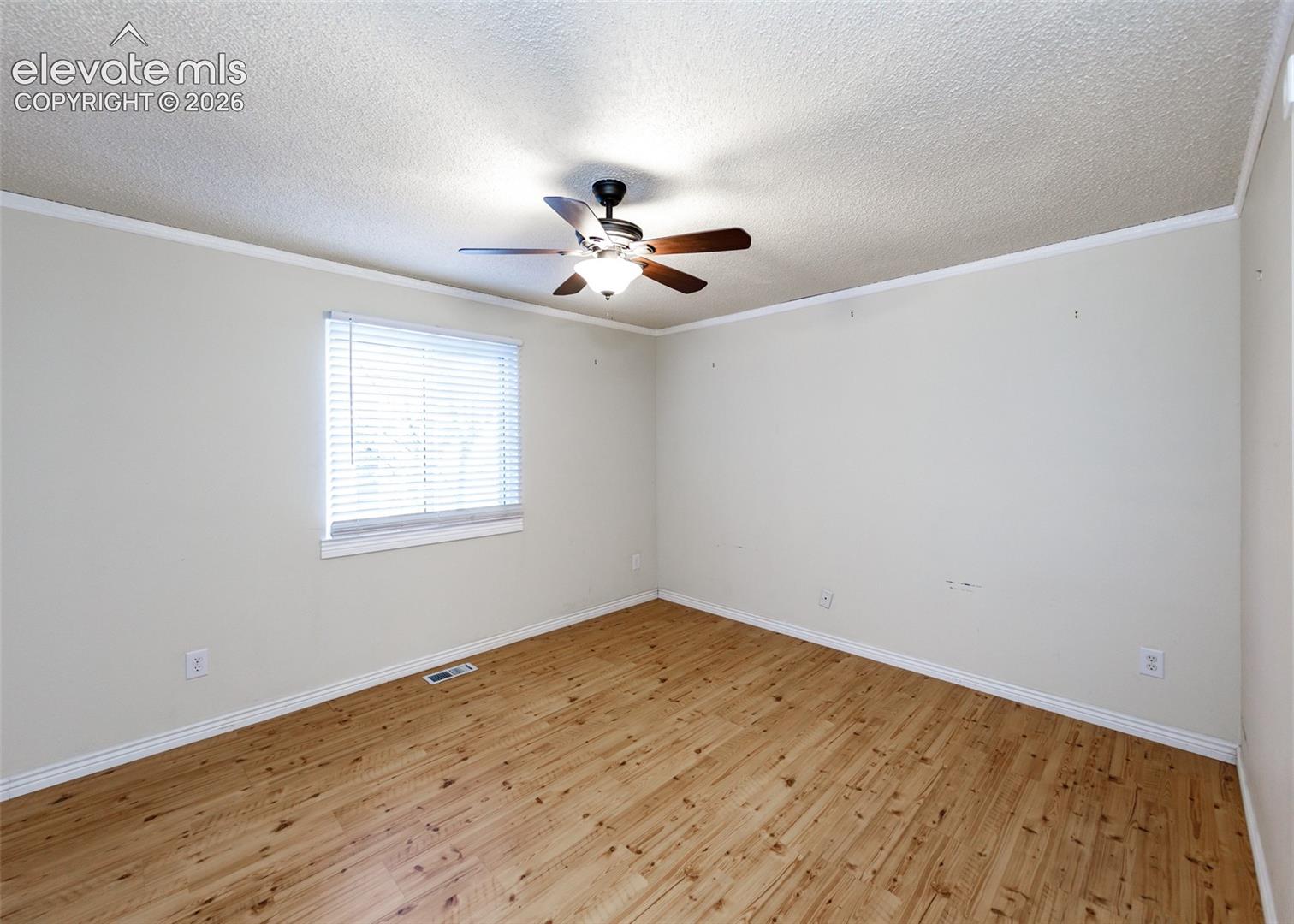Room featuring wood-finish flooring, a ceiling fan with integrated light fixture, and horizontal blind window treatments