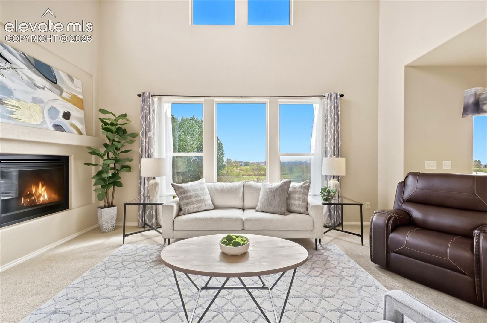 Open living room with high ceilings, tons of natural light, and a gas fireplace