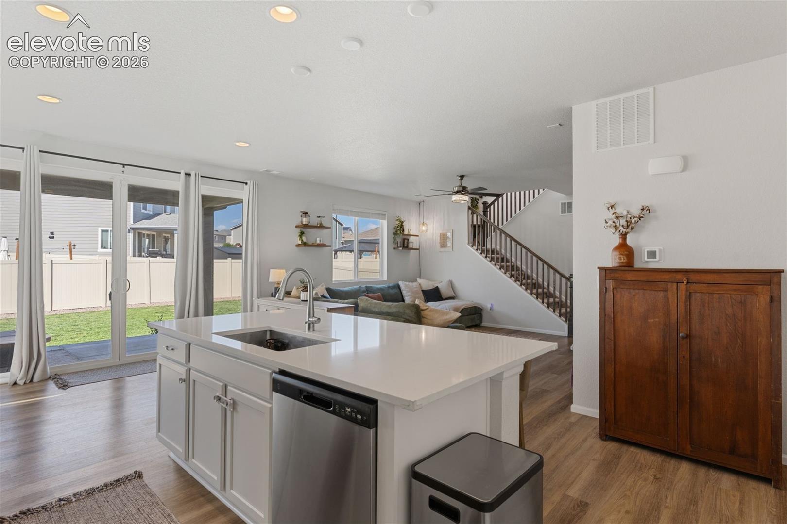 Kitchen island with an undermount sink, stainless steel dishwasher, and white cabinetry