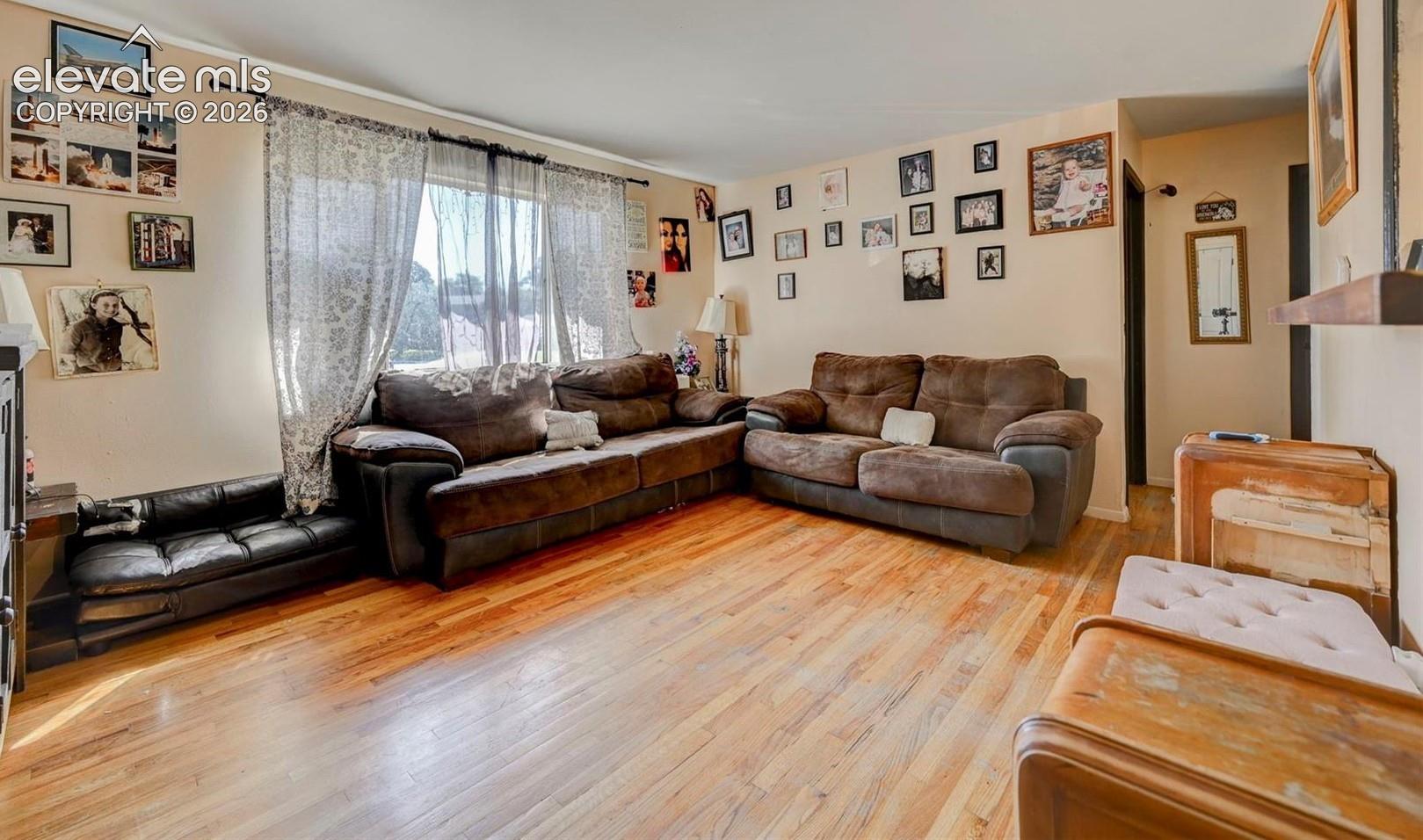 Living area featuring wood-finish flooring and a large window with a curtain rod