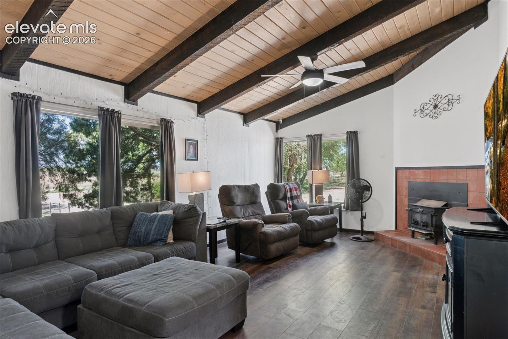 Interior living area of 16885 featuring vaulted wood ceilings with exposed beams, natural light, and a wood-burning stove