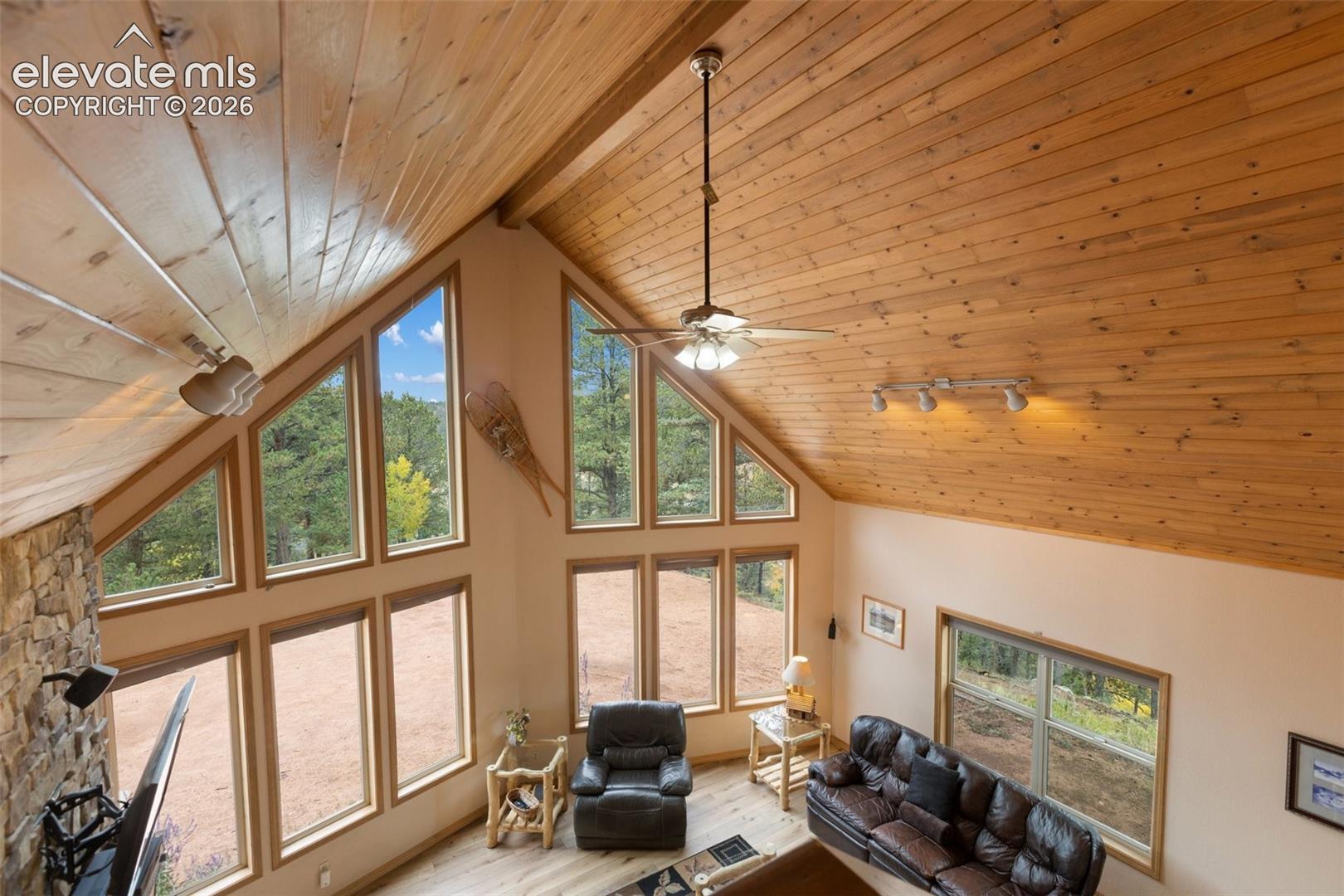 Vaulted wood-paneled ceilings, a stone accent wall, and a full wall of windows