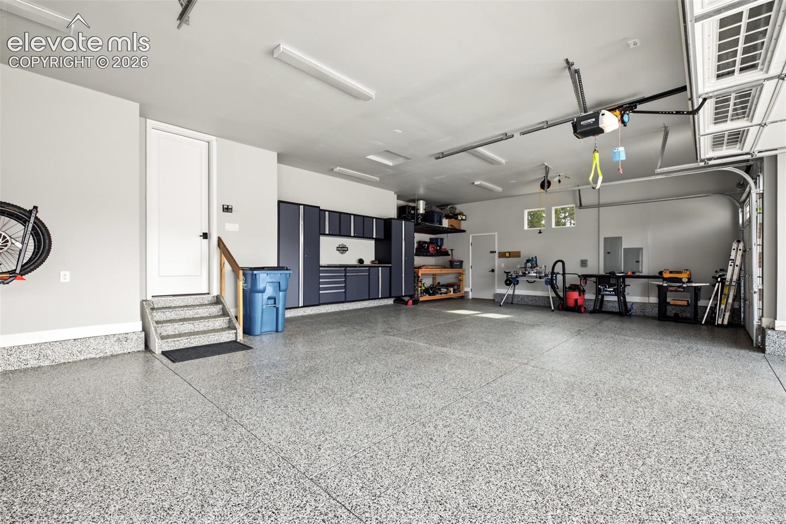 Impressive oversized four-car garage featuring professionally installed floor coating, finished and insulated walls, premium NewAge Pro cabinetry, and upgraded electrical, including 50-amp prewiring.