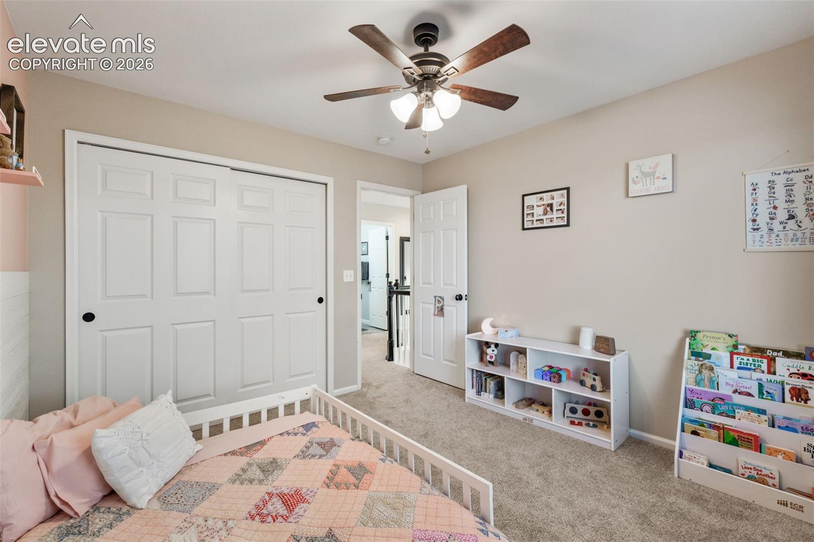 Room featuring neutral wall paint, carpeting, a ceiling fan with integrated lighting, and a closet with double sliding doors