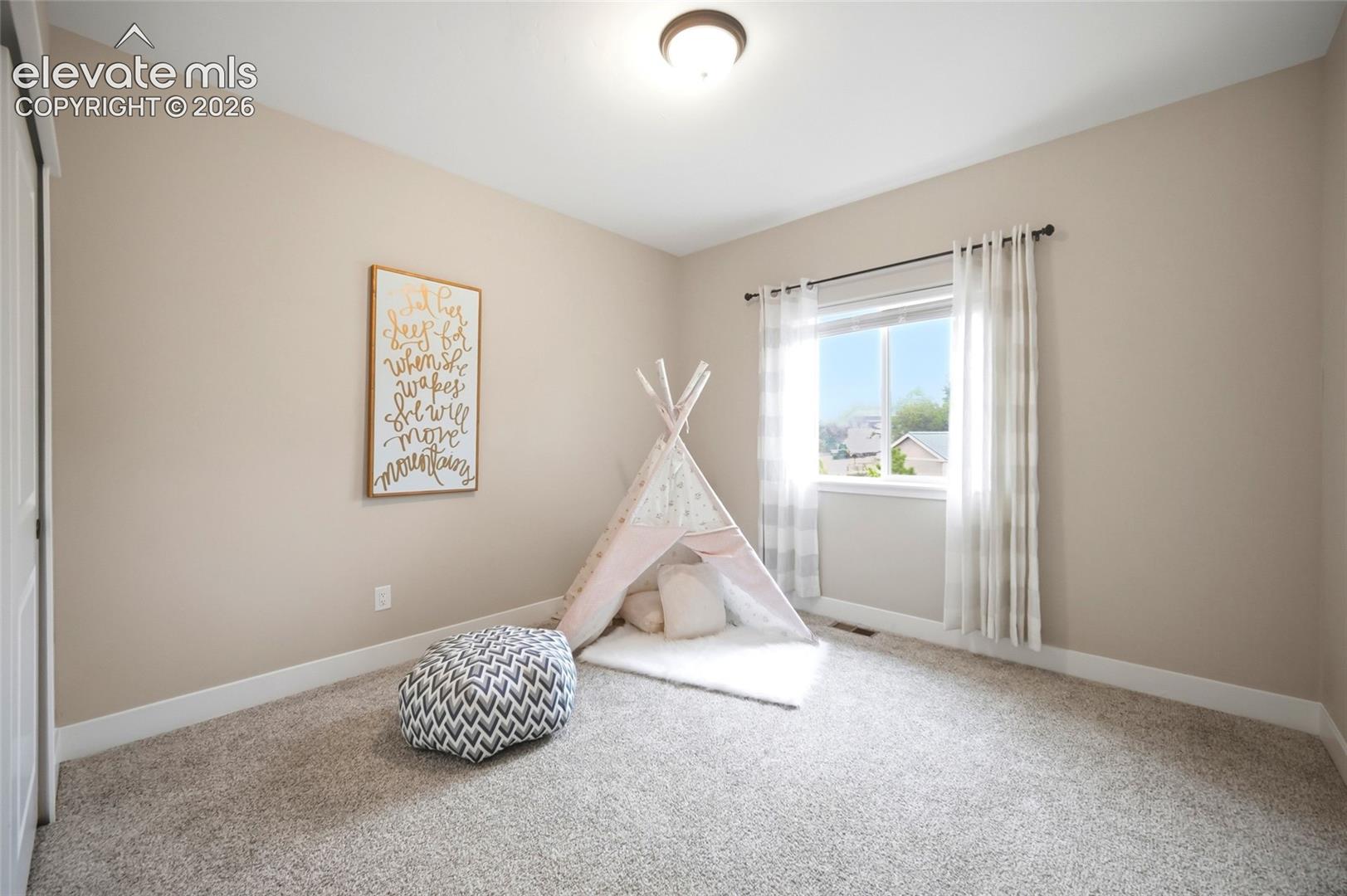 Neutral-toned interior room featuring plush wall-to-wall carpeting, a dual-pane window, and a central ceiling-mounted light fixture