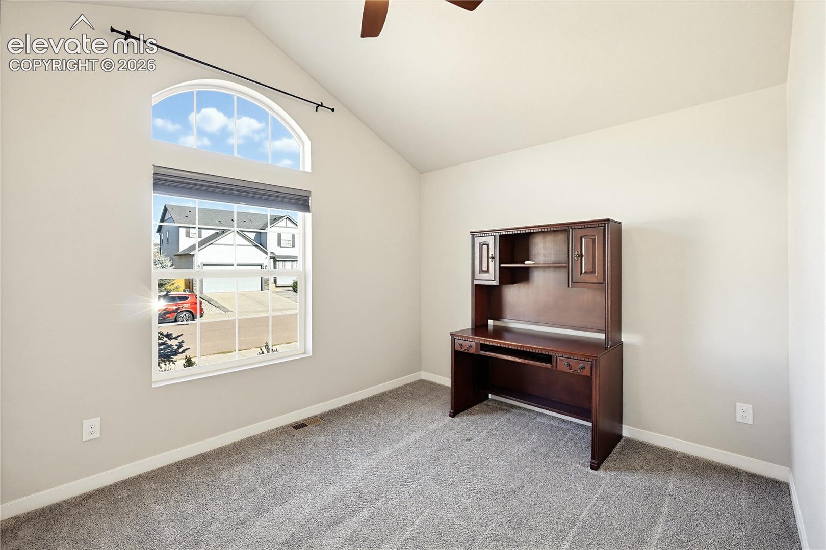 Vaulted ceiling with a central fan, arched window, and wall-to-wall carpeting