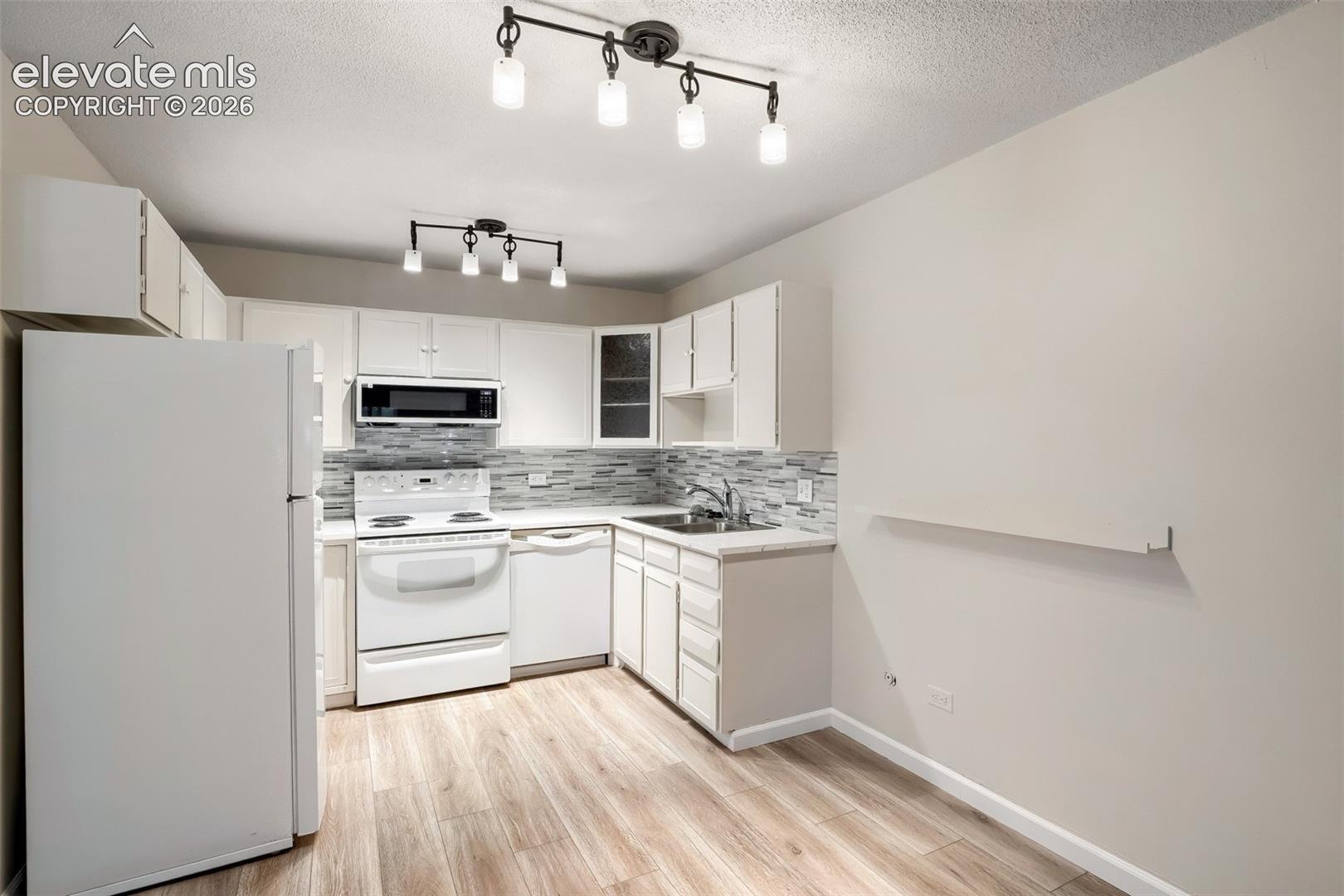 Kitchen featuring wood-finish flooring and white cabinetry