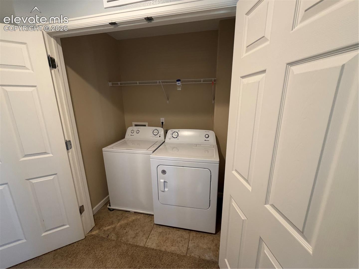 Laundry closet featuring neutral wall tones, tiled flooring, and a wire shelving unit
