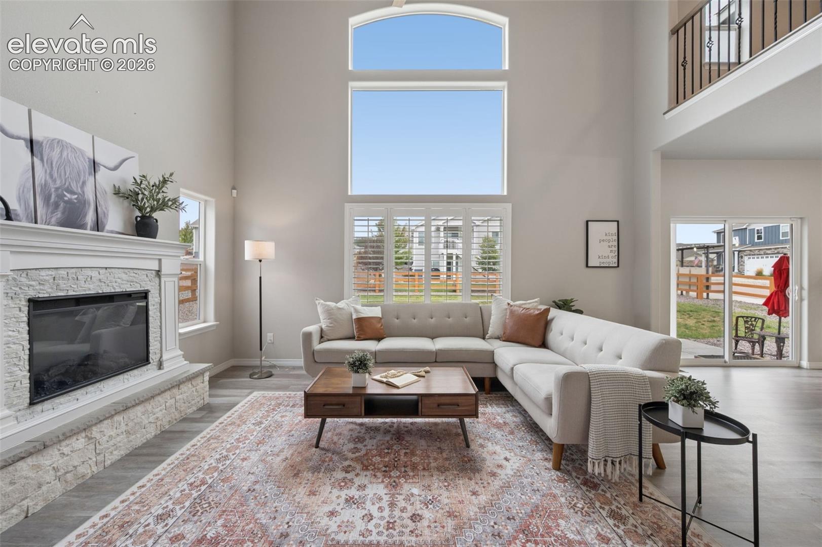 Two-story living area with high ceilings, large windows with shutters, and wood-finish flooring