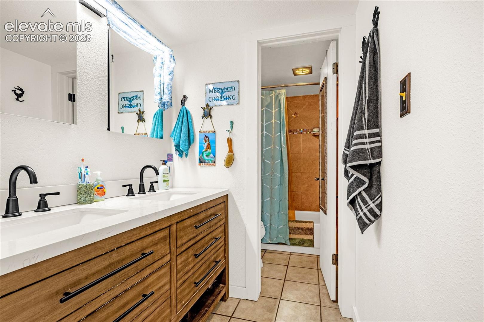 Double vanity with undermount sinks, wood-finish cabinetry, matte black fixtures, and a white countertop