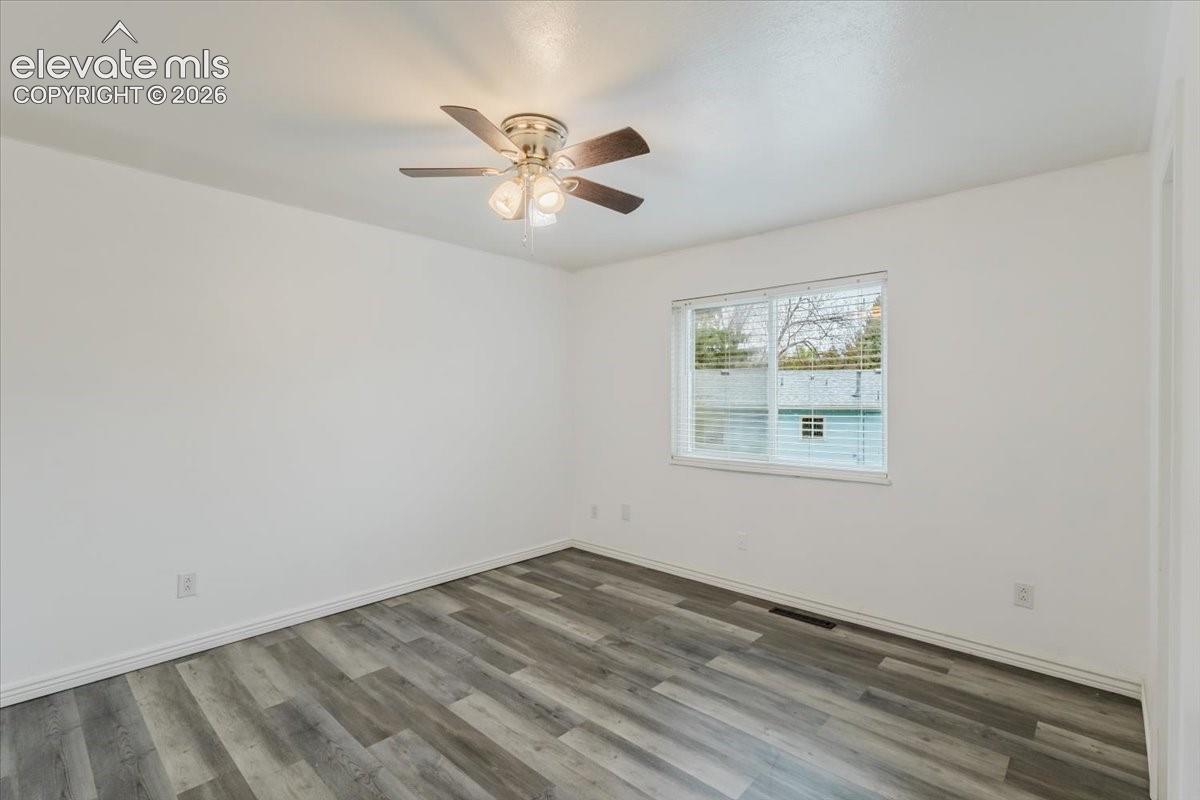 Room featuring wood-finish flooring, white baseboards, and a contemporary ceiling fan with integrated lighting