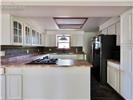 Kitchen featuring white shaker-style cabinetry, glass-front upper cabinet doors, stone-finish backsplash, recessed lighting, and a gas cooktop set within a countertop peninsula
