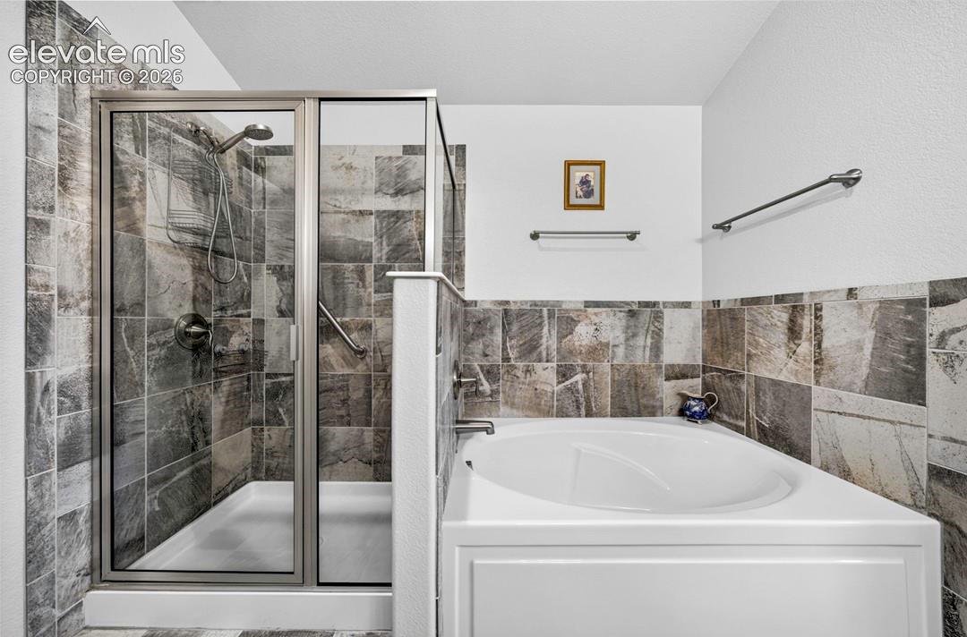 Bathroom with a tiled shower enclosure featuring a glass door and an adjacent built-in soaking tub