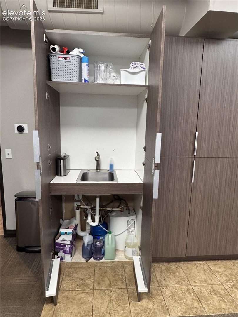 Built-in cabinetry with a stainless steel sink and integrated faucet, complemented by a tiled floor
