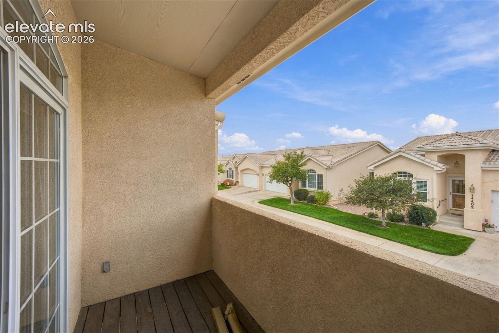 Covered balcony featuring stucco walls, wood-finish flooring, and arched window pane detailing