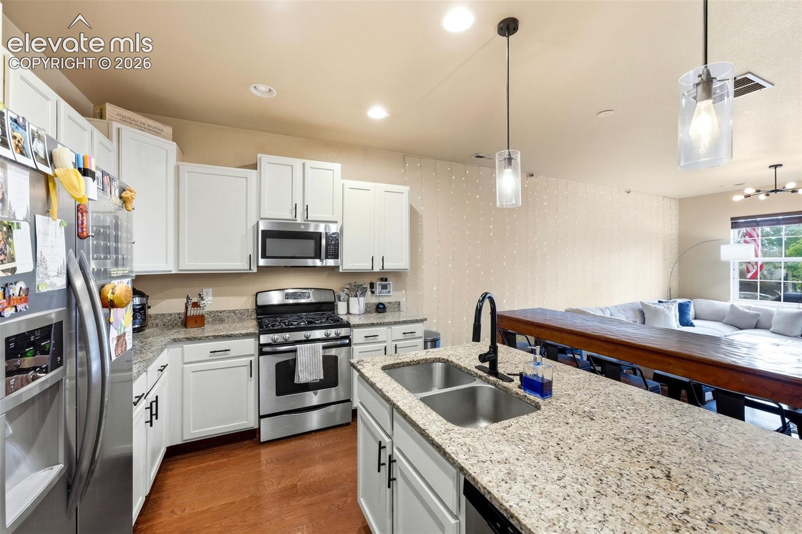 Kitchen featuring white cabinetry, stainless steel appliances, wood-finish flooring, and light-toned countertops