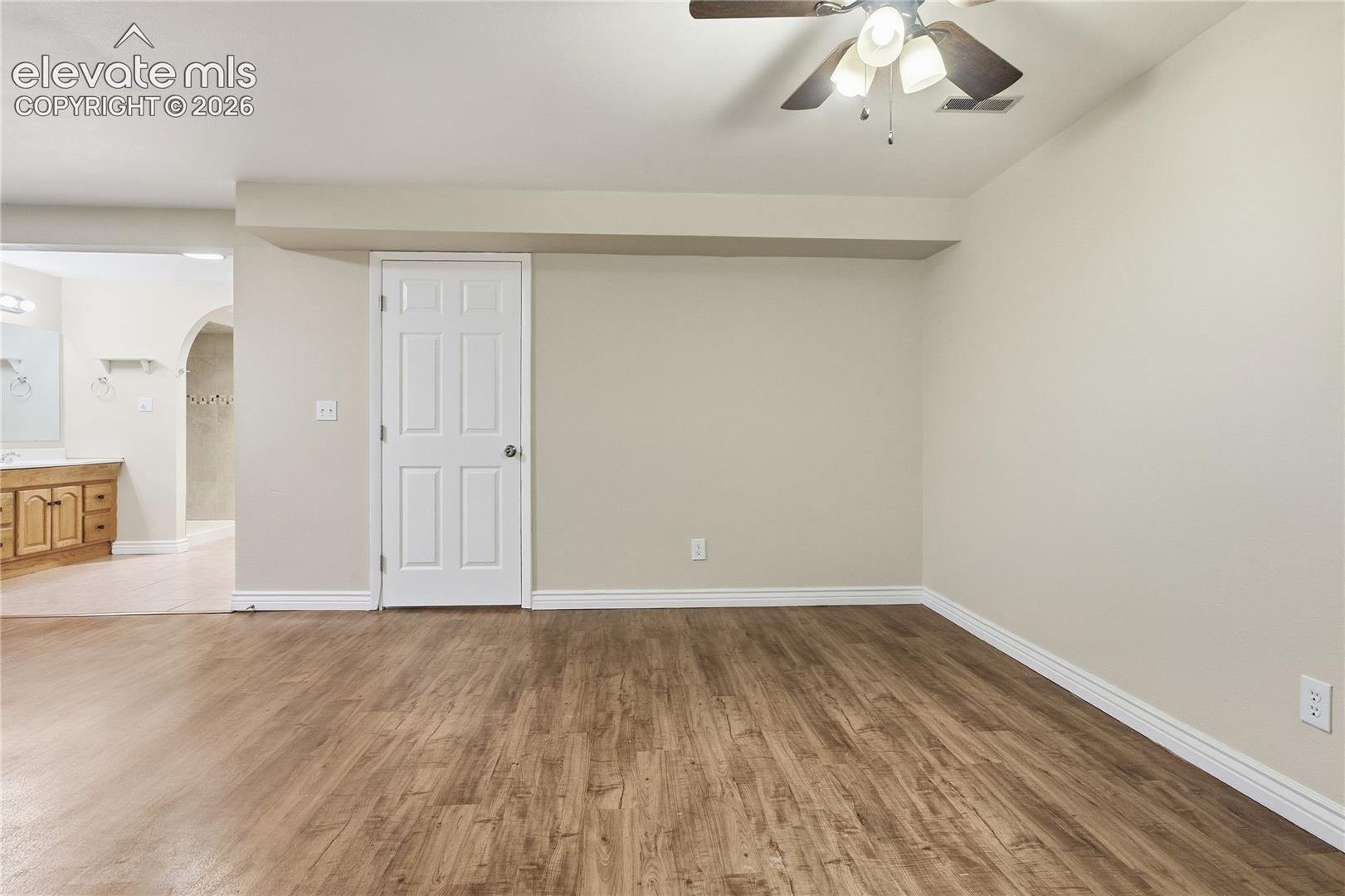 Wood-finish flooring throughout, with neutral wall tones and a ceiling fan