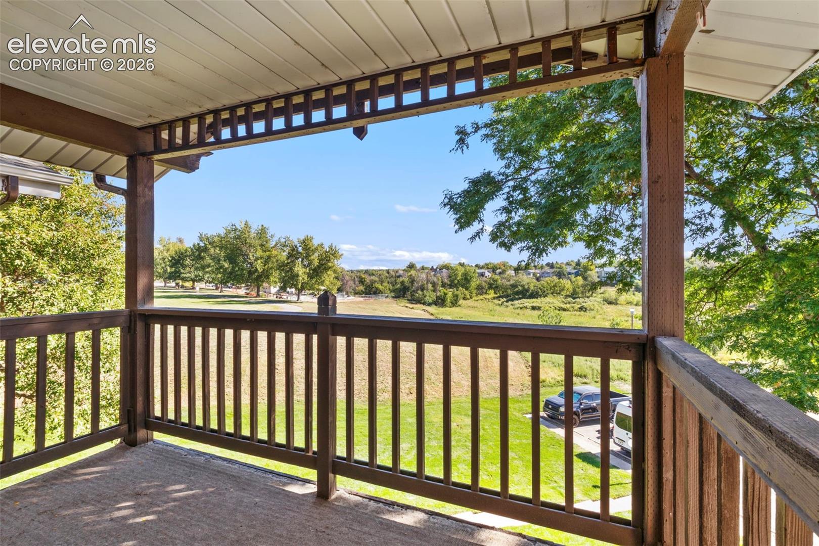 Covered balcony with wood railings and open outdoor scenery