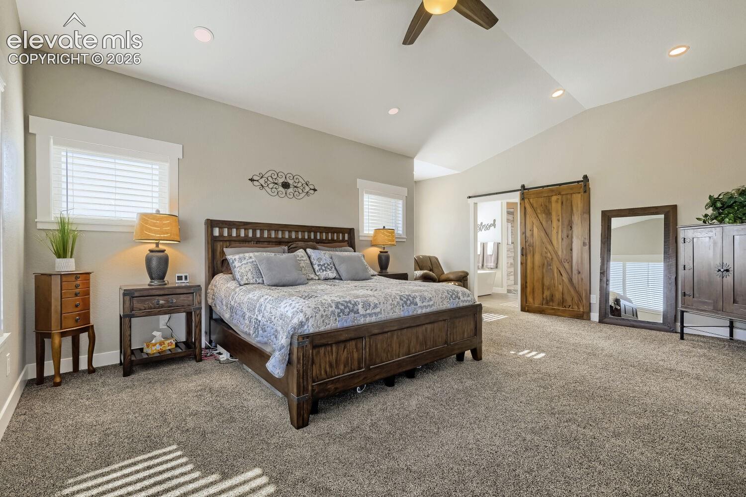Vaulted ceiling with a ceiling fan, recessed lighting, and a sliding barn door