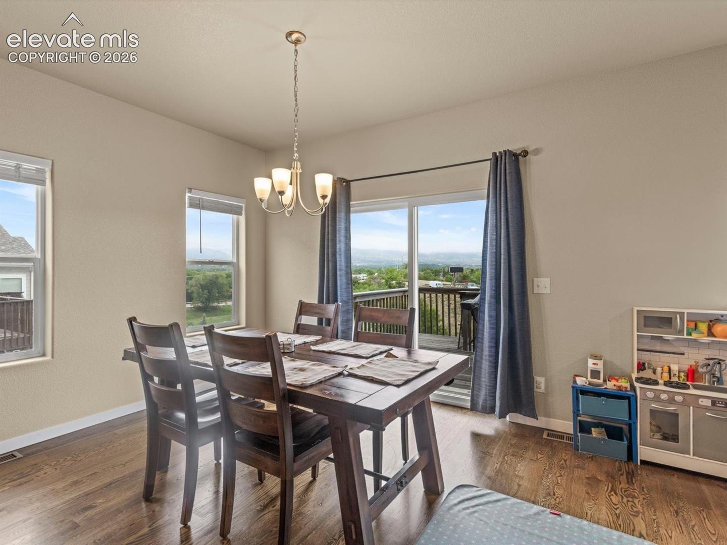 Dining space featuring wood-finish flooring, a contemporary chandelier, and a sliding glass door opening to a balcony
