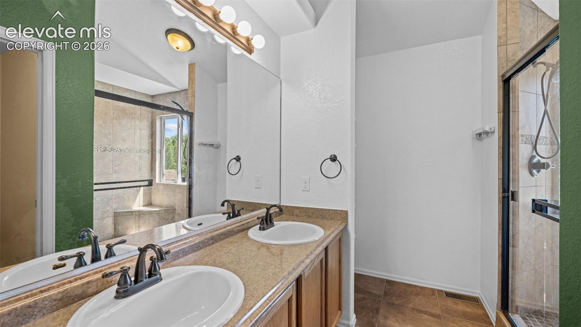 Primary bath with dual sinks and walk-in shower with dual shower heads.