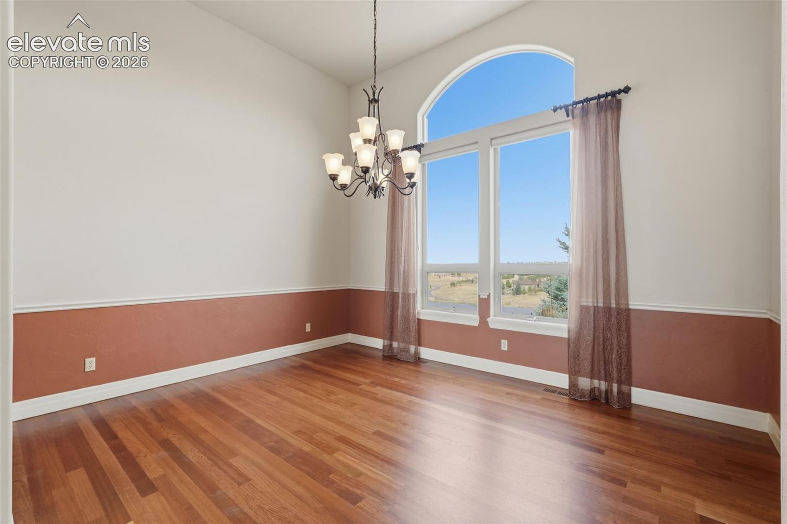 Spacious interior featuring a vaulted ceiling and a large arched window