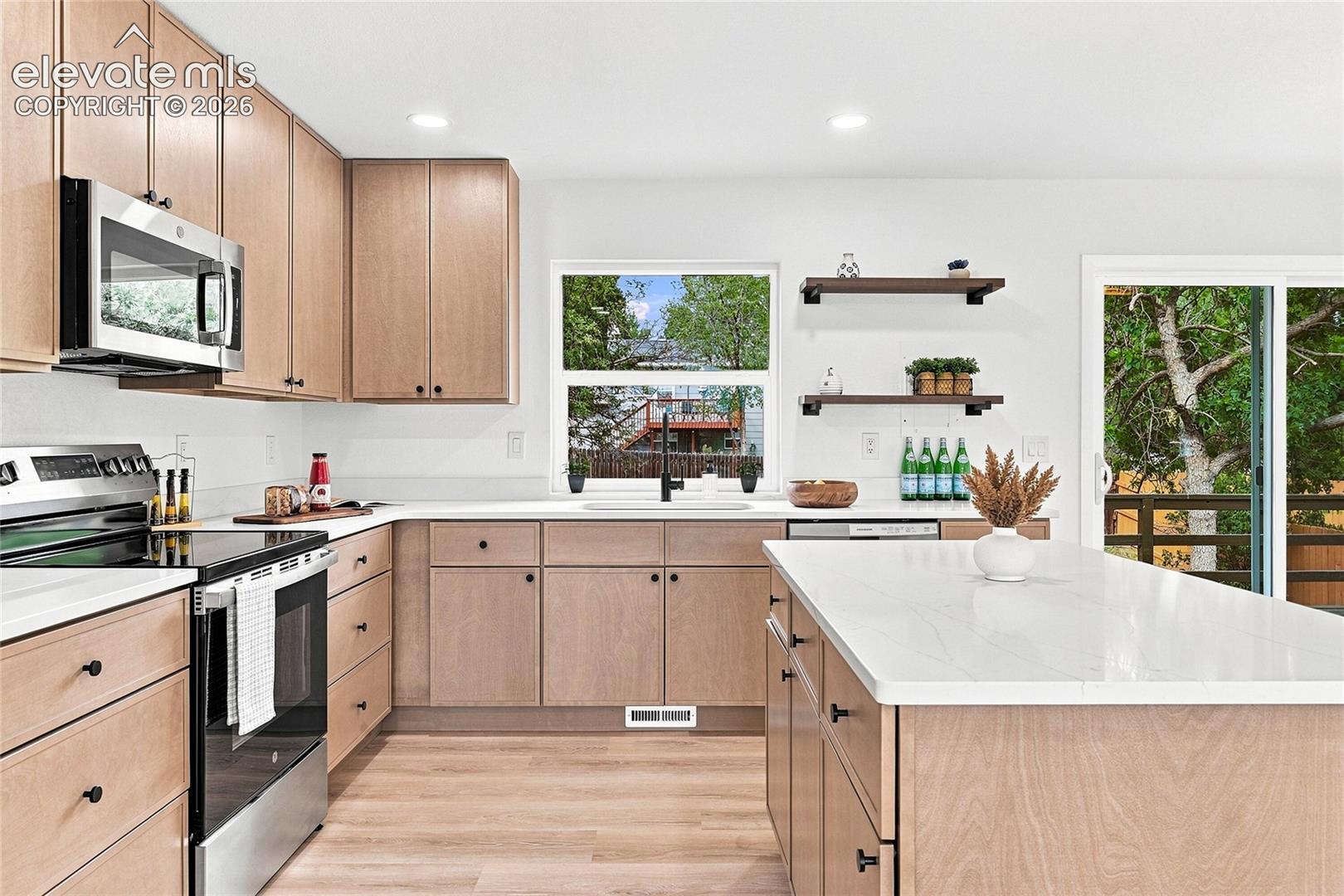 Kitchen featuring wood-finish cabinetry, stainless steel appliances, a center island with a white countertop, and wood-finish flooring