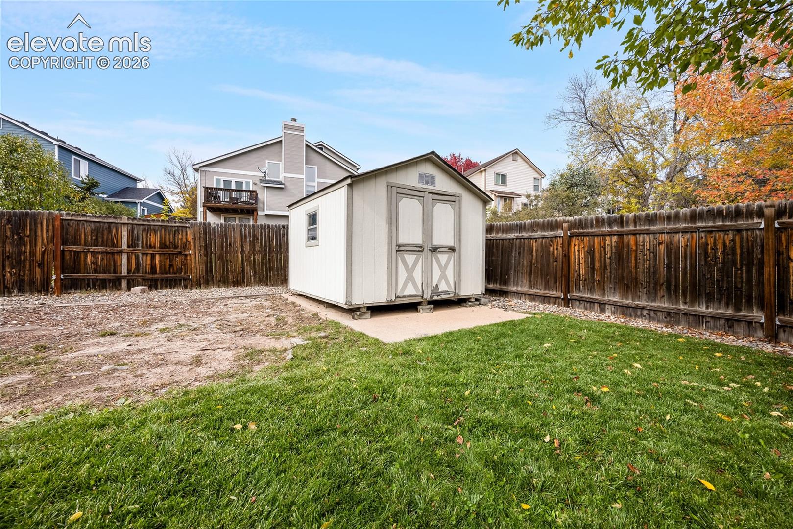 Rear yard featuring a detached storage shed on a concrete pad, enclosed by a wood privacy fence and a manicured lawn