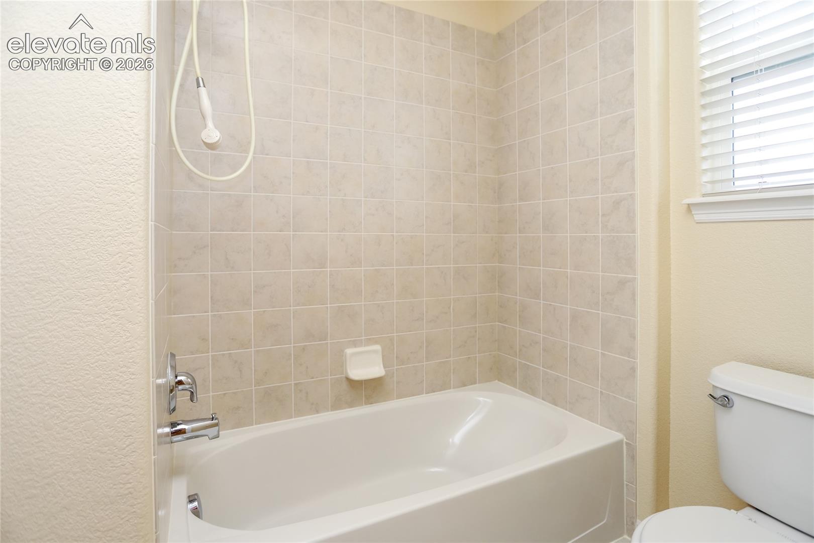 Tub/shower area is conveniently separated by a door from the vanity area in the upper bathroom.