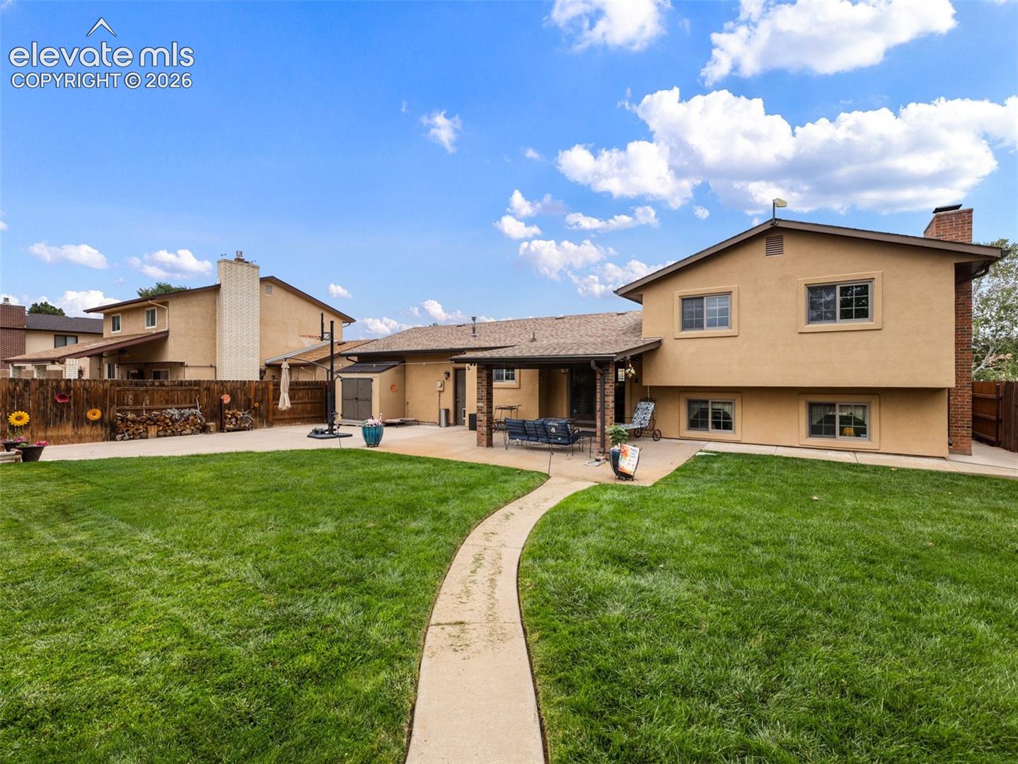 Expansive green lawn with a curved concrete pathway and a stucco exterior home
