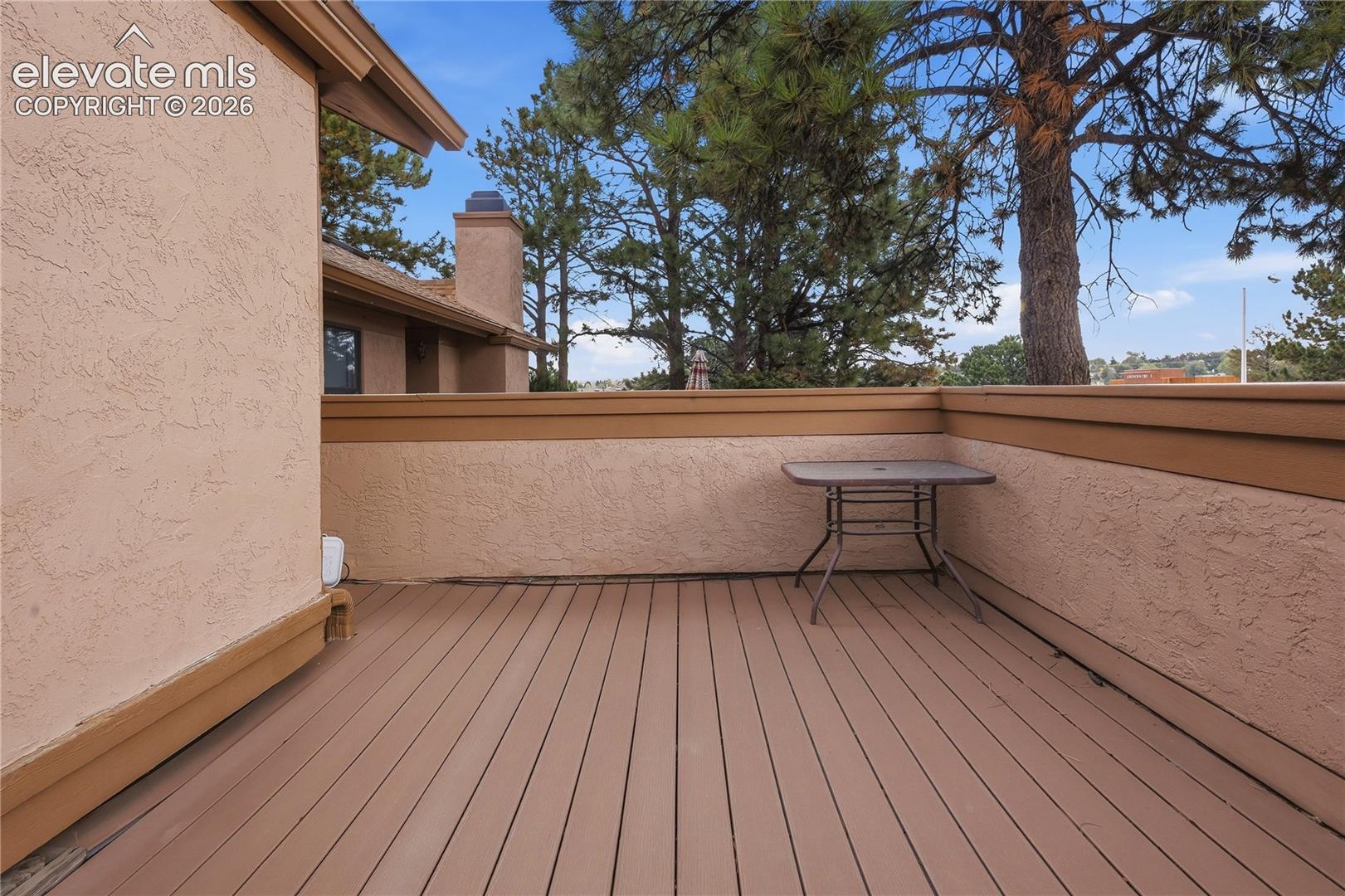 Expansive patio featuring composite decking, stucco exterior walls, and a prominent chimney structure